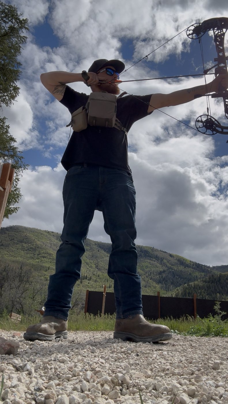 Matt Barber at full draw with his compound bow in the mountains